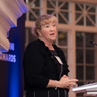 Woman talking into microphone and looking toward the right side of the room